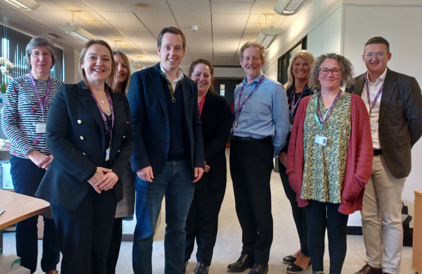 Tom posing for a group photograph with a group of representatives from Age UK Northamptonshire. The group are all smiling.