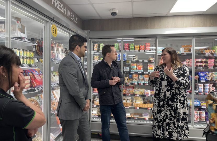 Tom in conversation with a group of staff members from the Co-op. They are all standing in front of a chiller holding various produce.